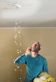 Man with water flooding through the ceiling